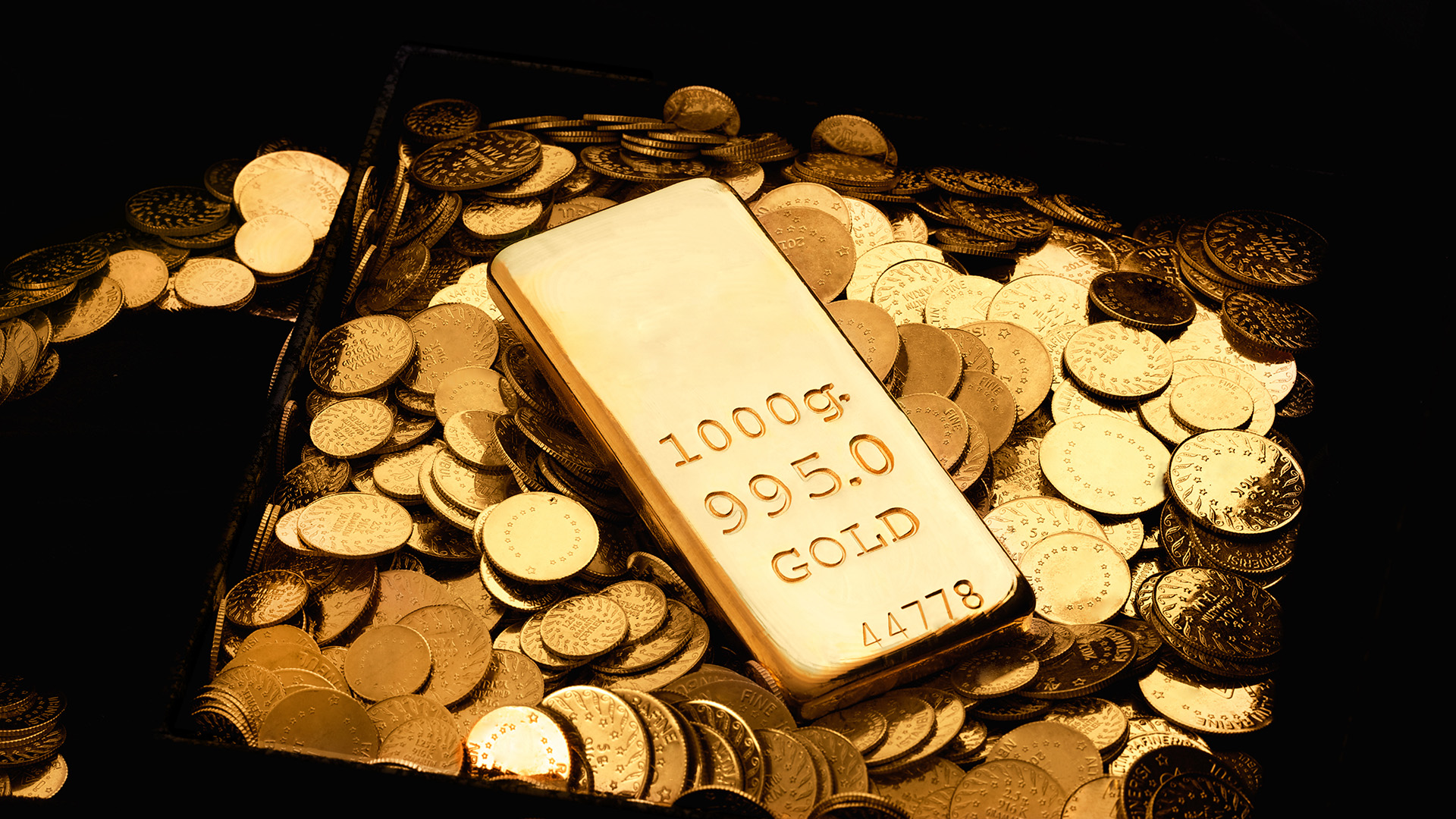 1 gold bar surrounded with gold coins amid Gold Prices Are Below $2,000 Per Ounce